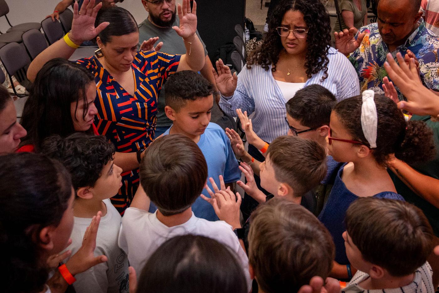 Crianças e adultos orando juntos durante a conferência